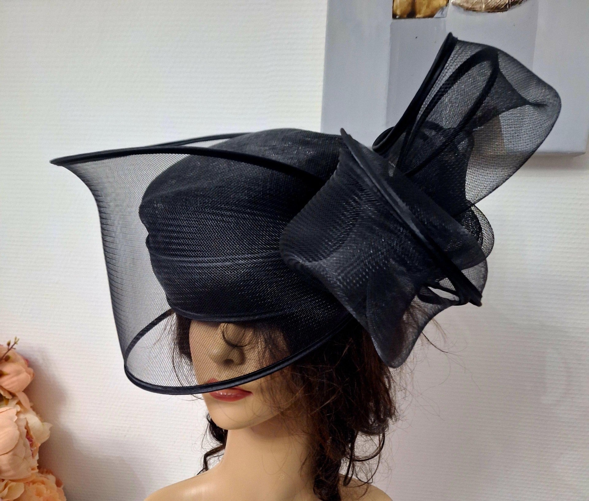 Ce chapeau de cérémonie noir incarne l'élégance intemporelle pour vos moments les plus importants. Doté d'un large bord généreux et d'un nœud raffiné, il combine sophistication et charme avec une grâce naturelle. Conçu pour les mariages, les événements formels et les occasions spéciales, cet accessoire de prestige ajoute une dimension remarquée à votre silhouette. Chaque détail a été pensé avec soin : la structure généreuse du bord offre une présence imposante et élégante, tandis que le nœud délicat apporte