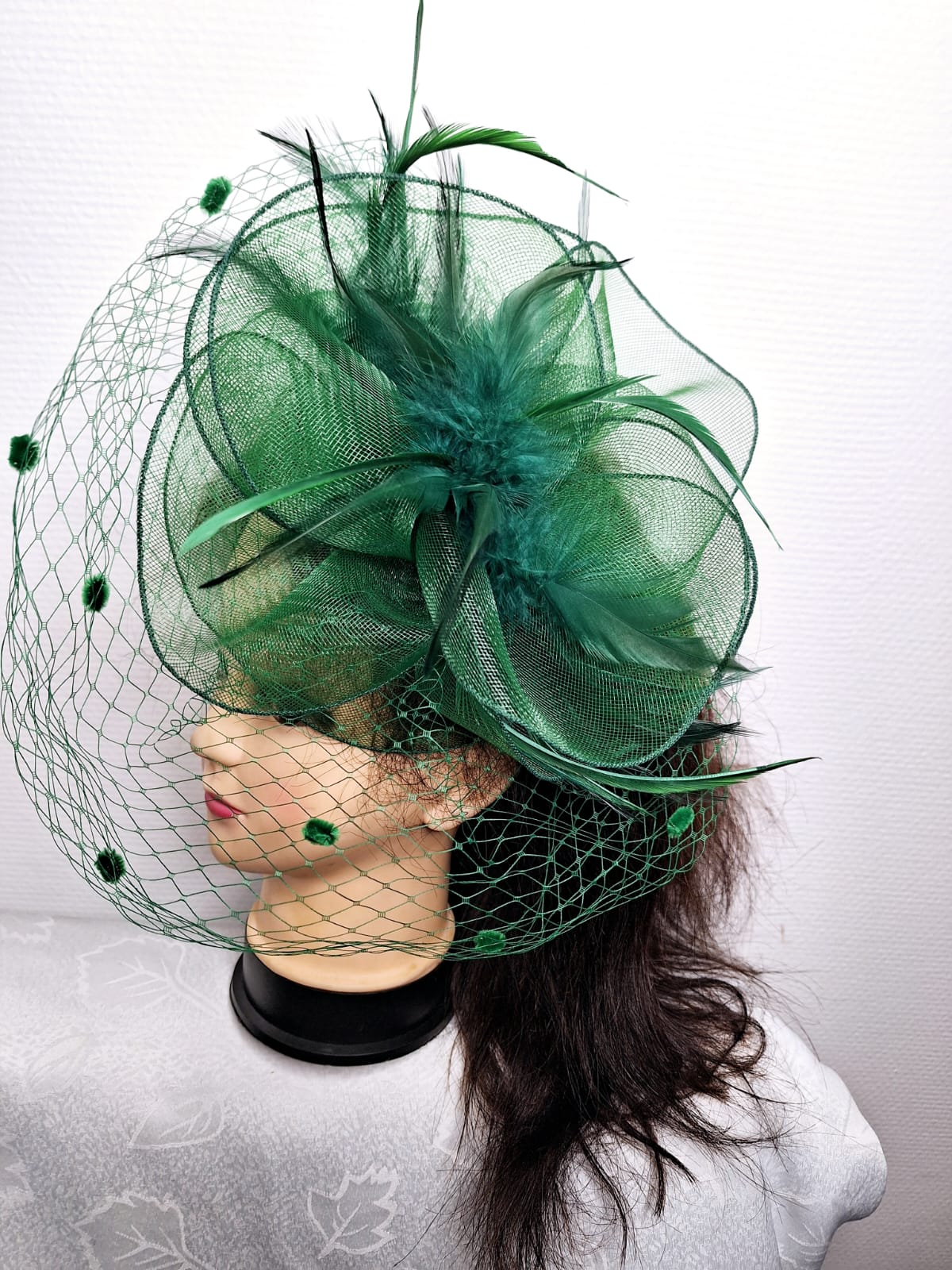 Ce chapeau de cérémonie vert est un accessoire d'exception conçu pour les moments importants. Orné d'un délicat grillage et de plumes sophistiquées, il combine élégance intemporelle et détails raffinés. Sa teinte riche crée une présence remarquable, tandis que les éléments texturés apportent légèreté et dimension à votre silhouette. Parfait pour les mariages, galas et événements formels, ce chapeau affirme votre style avec assurance et distinction. Un choix idéal pour celles qui recherchent un accessoire mé