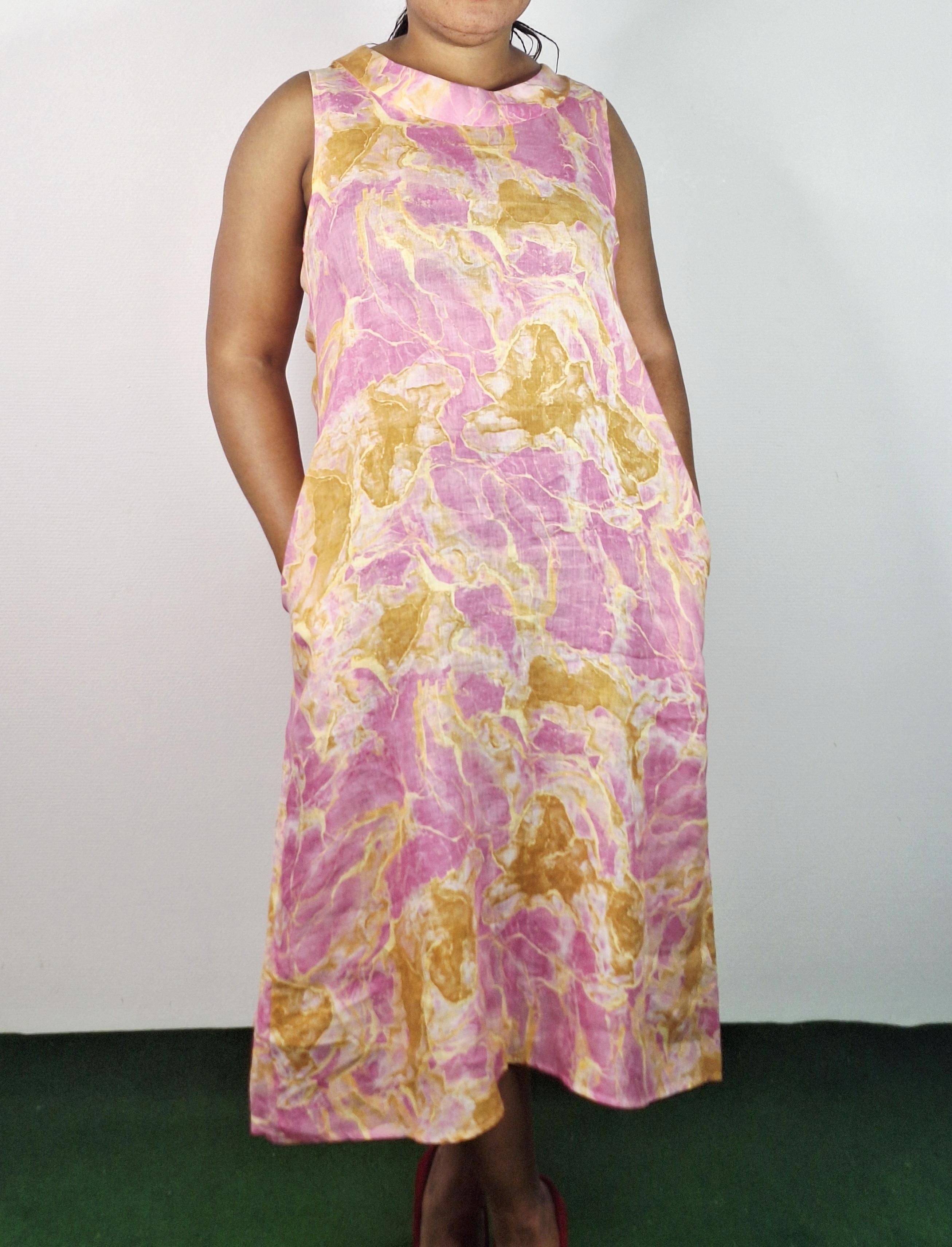 Découvrez cette robe rose en lin ornée d’un délicat motif doré, conçue pour s’adapter parfaitement grâce à sa taille unique. Sans manches et avec un col rond flatteur, elle offre une allure élégante et légère, idéale pour les journées chaudes. Sa coupe polyvalente met en valeur toutes les silhouettes, faisant de cette robe un choix parfait pour allier confort et style avec sophistication