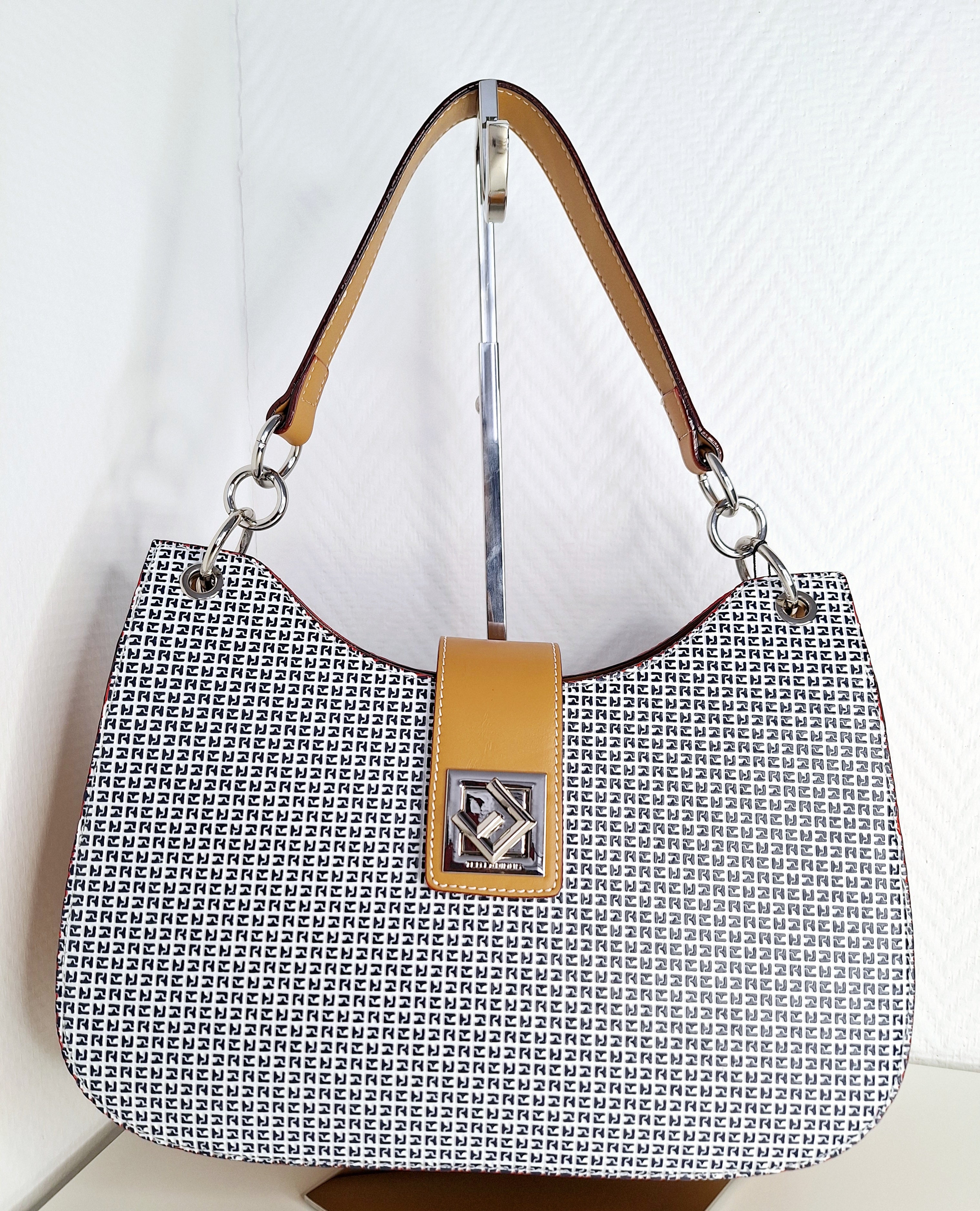 Ce sac à main Ted Lapidus incarne l'élégance intemporelle avec son design tricolore subtil associant le marine profond, le blanc pur et les nuances miel. Confectionné pour les femmes en quête de polyvalence, il se distingue par sa silhouette épurée et ses proportions équilibrées qui complètent harmonieusement toute garde-robe. Ses trois teintes complémentaires offrent une flexibilité remarquable : du bureau aux sorties en soirée, ce sac s'adapte sans effort à vos différents styles et occasions. La combinais